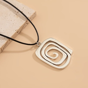Makroaufnahme von silbernem Spiral-Quadratanhänger an schwarzer Kordel auf Naturstein
