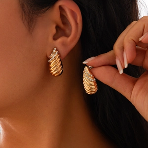 Gros plan détaillé des boucles d'oreilles dorées à texture coquillage et strass