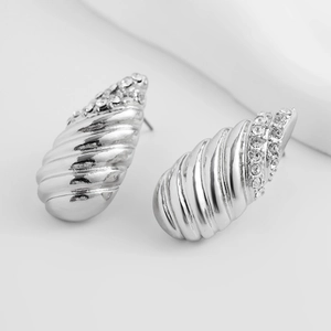 Détail macro de boucles d'oreilles conque argentées avec incrustation de zircons