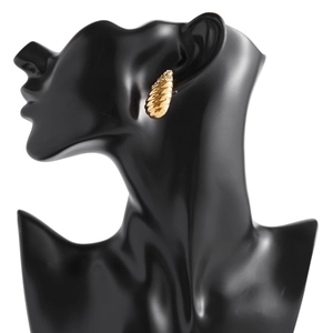 Détail d'une boucle d'oreille spirale dorée avec zircons brillants sur mannequin noir