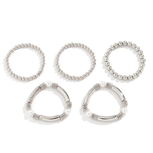 Detalle de set de cinco pulseras plateadas con cuentas, lazo, perlas y tubos metálicos