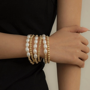 Primer plano de un set de seis pulseras con perlas y cuentas de metal dorado