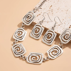 Nahaufnahme von Vintage-Silberkette und Ohrringen mit Spiralmuster auf Steinhintergrund