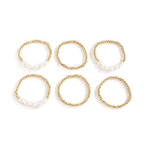 Detalle de un juego de 6 pulseras con cuentas de metal dorado y perlas blancas