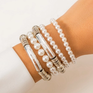 Detalle de un juego de cinco pulseras con perlas blancas y tubos de metal plateado