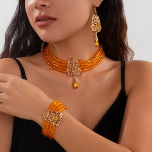 Detalle del conjunto de perlas naranjas con piezas de metal dorado calado de estilo floral