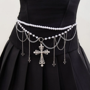 Macro detail of gothic waist chain featuring layered metal tassels and a cross pendant