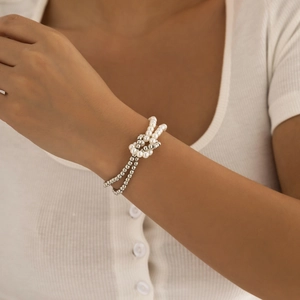Detalle de una pulsera multicapa con perlas blancas y cuentas de plata pulida en la muñeca