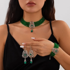 Detalle de un conjunto de joyas vintage con cuentas verdes y diseño calado plateado