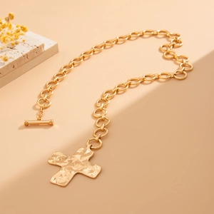 Detail van gouden OT-gespketting met gehamerde kruishanger en hartvormige accenten