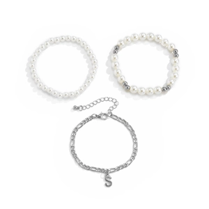 Detalle de un juego de tres pulseras de perlas y cadena plateada con colgante de S