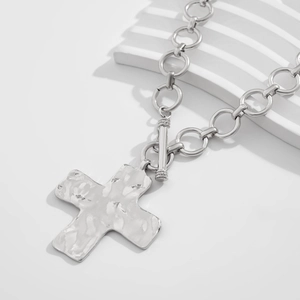 Detail van zilveren kruis ketting met OT-sluiting en gehamerde textuur op de hanger