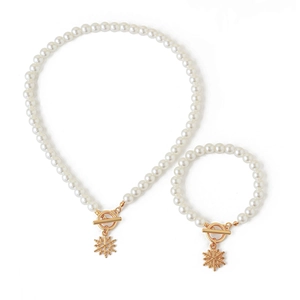 Nahaufnahme von weißer Perlenkette und Armband mit goldenem Schneeflockenanhänger und OT-Verschluss