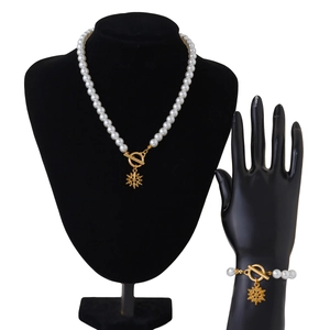 Detaillierte Ansicht von Perlenkette und Armband mit goldenem Schneeflockenanhänger und OT-Verschluss
