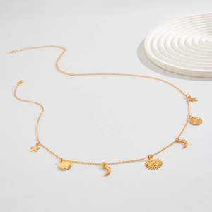 Detail of golden body chain featuring celestial charms like star, moon and sun motifs