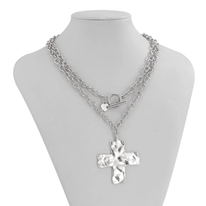 Detail van een zilveren punkketting met dubbele lagen, een groot gehamerd kruis en hart