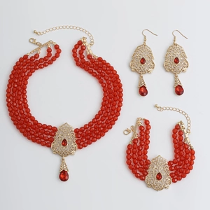 Detalle del juego de joyas rojas de varias capas con colgante de gota y motivos florales retro