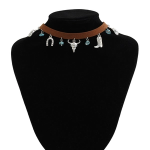 Détail du collier choker western avec charms crâne de taureau, fer à cheval et botte