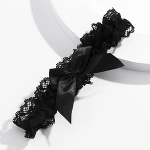 Détail d'une jarretière en dentelle noire avec nœud en satin sur socle blanc