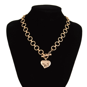 Detailopname van een gouden hartvormige lava hanger met textuur aan een dikke ketting