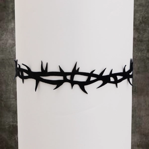 Gros plan d'un choker noir mat au design épines sur un support cylindrique blanc