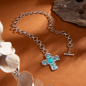Detail van punk zilveren ketting met turkooizen kruishanger en trendy OT-sluiting
