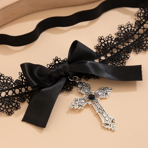 Detail eines schwarzen Spitzen-Strumpfbands mit Satinschleife und gotischem Kreuzanhänger