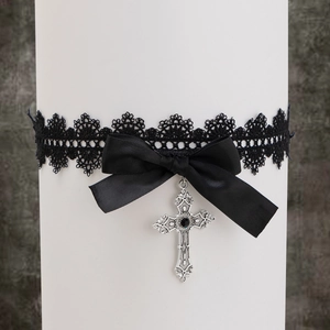Détail de la chaîne de cuisse en dentelle noire gothique avec nœud et pendentif croix