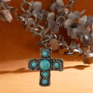 Detail van vintage bronzen kruis ketting met turquoise stenen en een OT-knebel sluiting