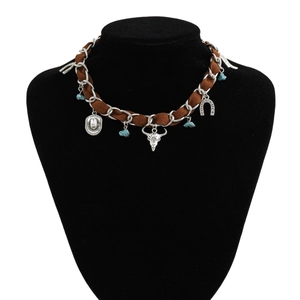 Détail du collier western avec crâne de taureau, breloques chapeau et turquoise sur velours