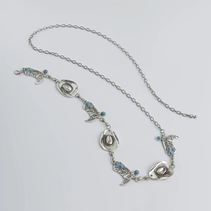 Detail van zilveren western lichaamsketting met cowboyhoed, laarsbedeltjes en turquoise accent