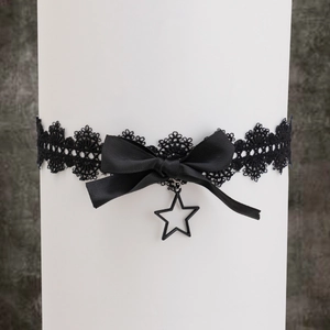 Détail d'un choker en dentelle noire avec nœud satiné et pendentif étoile gothique chic