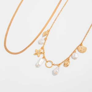 Macro detail of golden starfish, seashell charms and faux pearls on ocean style body chain