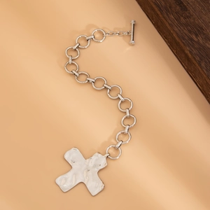 Detail van zilveren schakelarmband met gehamerde kruis hanger en toggle sluiting