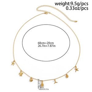 Detail of gold ocean body chain featuring starfish, shell, and turtle charms on a white base