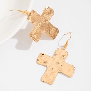 Detail van gouden kruis oorbellen met geborstelde en gehamerde metalen afwerkingen