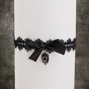 Détail de la jarretière gothique en dentelle noire avec nœud satiné et pendentif vintage