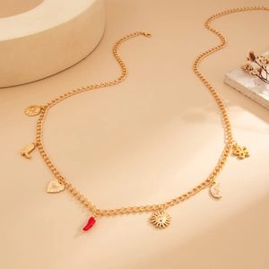 Macro detail of golden body chain with starfish and red chili pendant charms