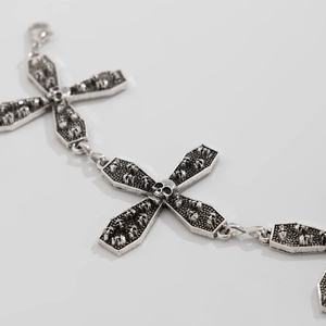 Close-up of gothic silver body chain featuring cross links and skull relief details