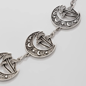 Detailed macro view of moon and mushroom pendant on a gothic silver body chain