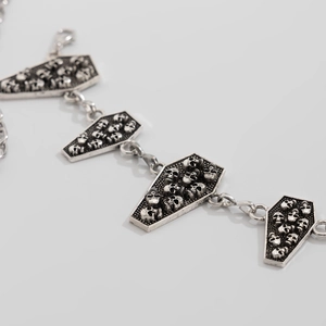 Macro detail of gothic silver coffin links with skull embossed patterns for body chain