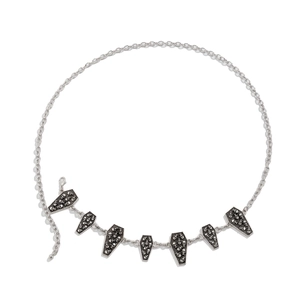 Macro detail of gothic silver waist chain with coffin pendants and skull relief