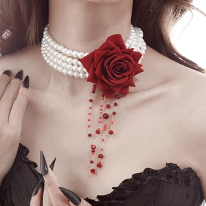 Detail of gothic pearl choker featuring a dark red rose and blood-red bead tassels