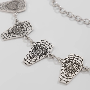 Detail of silver gothic body chain featuring coffin pendants with spider web and heart patterns