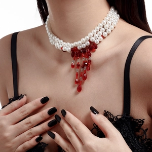 Close-up of triple-layer pearl choker with red crystal drop tassels for gothic look