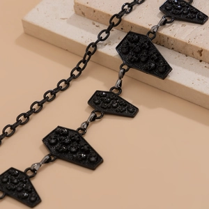 Gothic body chain detail featuring black coffin pendants with skull relief on stone blocks