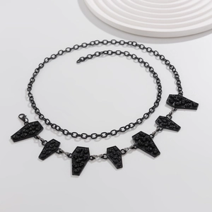 Macro shot of gothic black coffin pendants with skull carvings on a chain accessory