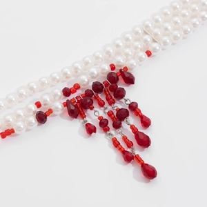 Detail of layered pearl necklace with red crystal tassels and blood-drop pendants