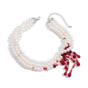 Detailed close-up of triple-layer pearl necklace featuring red crystal drop tassels