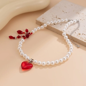 Macro shot of red crystal heart pendant on layered pearl necklace with blood-drop tassels